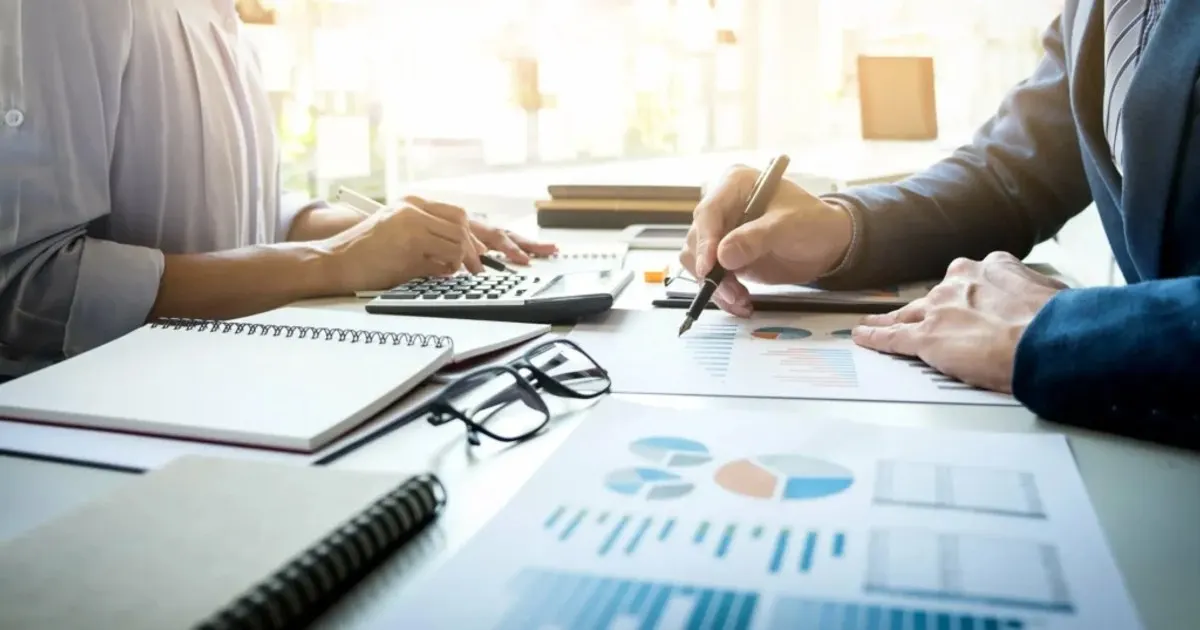 Two professionals reviewing financial charts and a calculator while planning business taxes